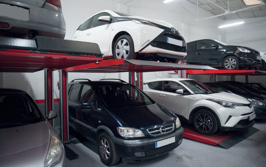 Row of car lifts with cars on top and beneath